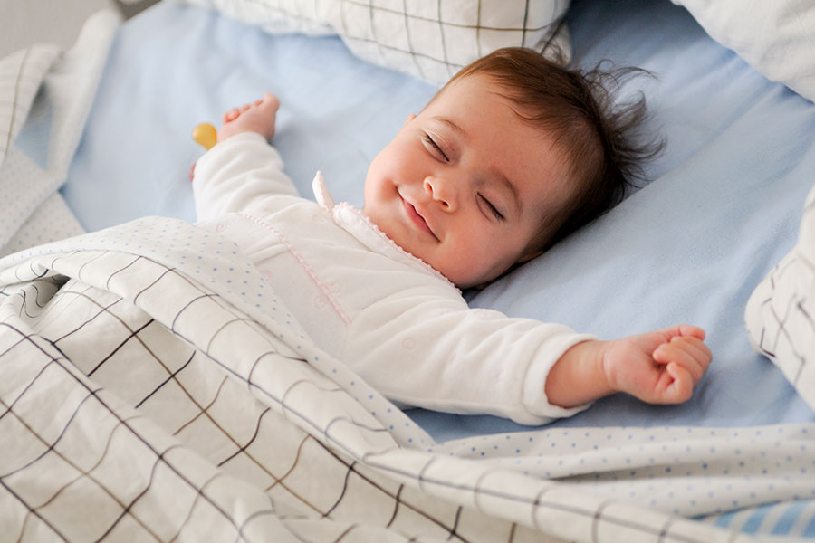 Bébé aux yeux rieurs endormi dans son lit